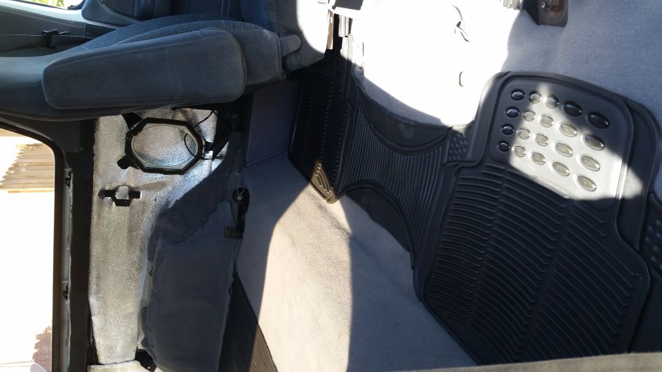 Car interior showing driver's side seat, door panel, and rubber floor mat