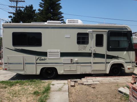 1995 Chevrolet P30 1 Ton - Step Van - This RV motorhome is parked outdoors on a sunny day, with a brick pathway in the foreground.