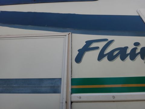 1995 Chevrolet P30 1 Ton - Step Van - Close-up of an RV's side panel, the 'Flair' decal and decorative stripes.