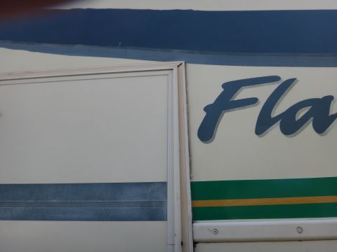 1995 Chevrolet P30 1 Ton - Step Van - A close-up view of a white step van with blue lettering that reads "Fla" and green and yellow stripes below. The image shows a portion of t…