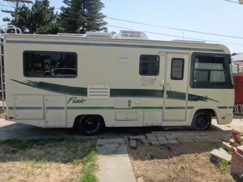 1995 Chevrolet P30 1 Ton - Step Van - Class C RV parked on a paved surface with trees and a fence in the background.
