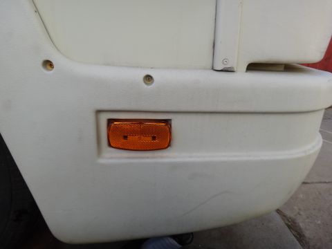 1995 Chevrolet P30 1 Ton - Step Van - Close-up of an orange reflector light mounted on the white bumper of a vehicle.