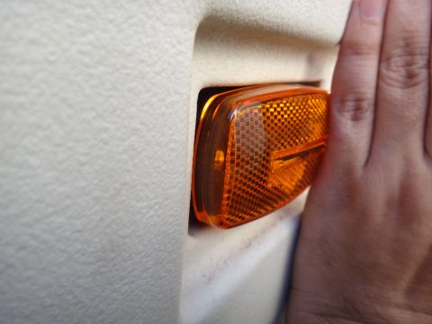 1995 Chevrolet P30 1 Ton - Step Van - A hand is shown installing an amber interior marker light into a vehicle's panel.