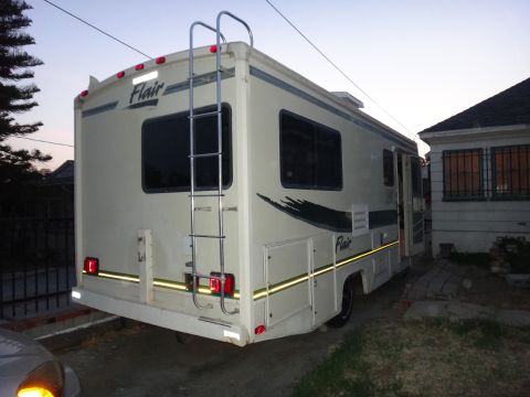 1995 Chevrolet P30 1 Ton - Step Van - Flair RV motorhome parked next to a house, showing the rear and side.