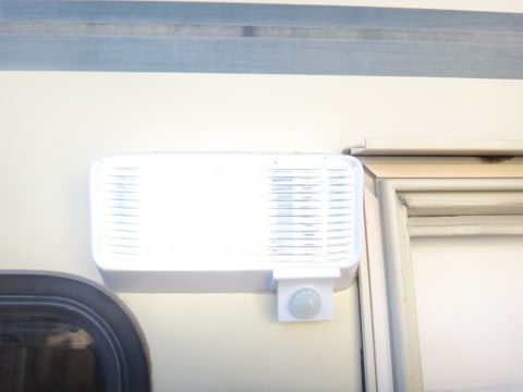 1995 Chevrolet P30 1 Ton - Step Van - Close-up of an RV exterior light fixture with a motion sensor attached.