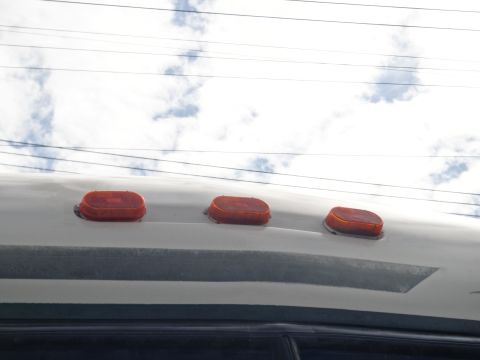 1995 Chevrolet P30 1 Ton - Step Van - The top of a vehicle shows three amber marker lights under a sky with clouds and power lines.