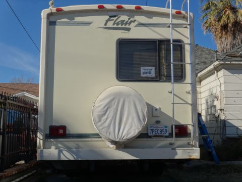 1995 Chevrolet P30 1 Ton - Step Van - The rear of a motorhome is visible, showing a spare tire cover and a ladder attached to the back.