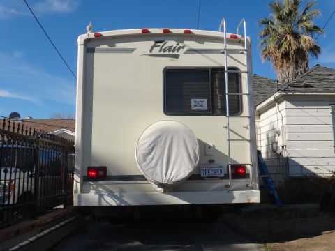 1995 Chevrolet P30 1 Ton - Step Van - Rear view of a Flair RV motorhome, showing its spare tire cover, ladder, and license plate.