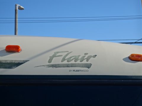 1995 Chevrolet P30 1 Ton - Step Van - The side of an RV with the 'Flair' branding by Fleetwood is visible against a blue sky.