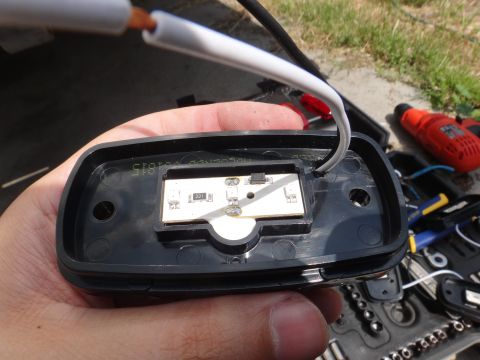 1995 Chevrolet P30 1 Ton - Step Van - A hand holds an LED light assembly, revealing its internal circuit board and wiring, with tools in the background.