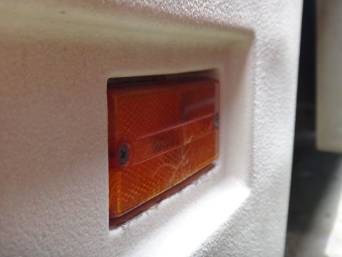 1995 Chevrolet P30 1 Ton - Step Van - Close-up view of an orange marker light assembly mounted on the textured white body of a step van.