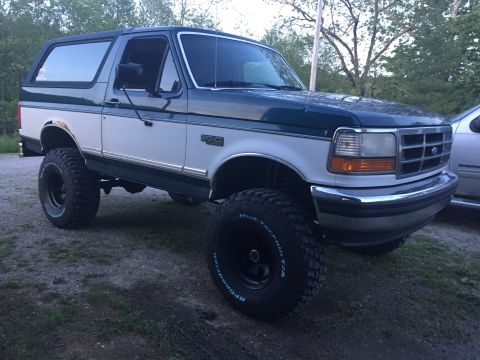 1994 Ford Bronco - This lifted 1994 Ford Bronco is shown in a three-quarter front view, highlighting its off-road tires and two-tone paint scheme.
