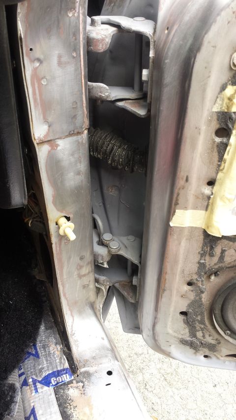 1976 Ford Ranchero - Close-up view of a vehicle's door jamb, showing the hinge assembly and a protective conduit for wiring.