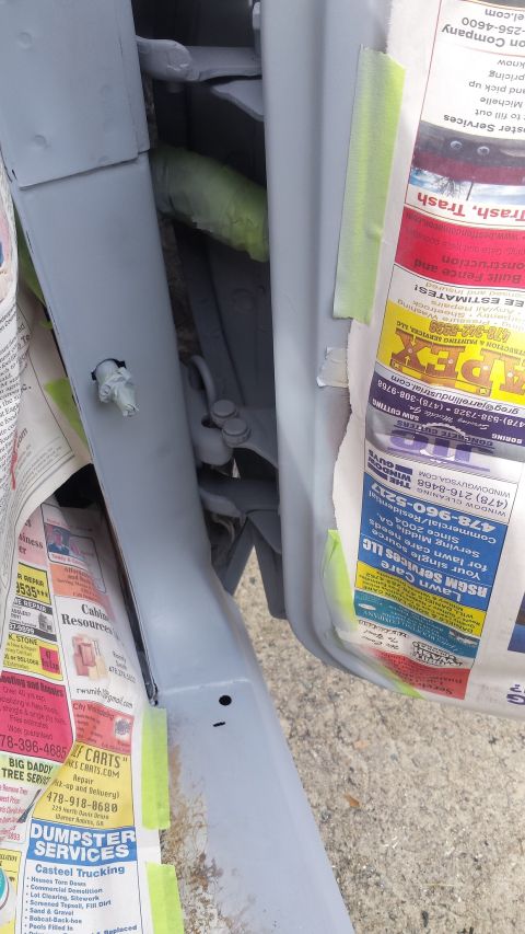 1976 Ford Ranchero - Close-up of a car's door jamb, covered in newspaper and tape, revealing internal hardware.
