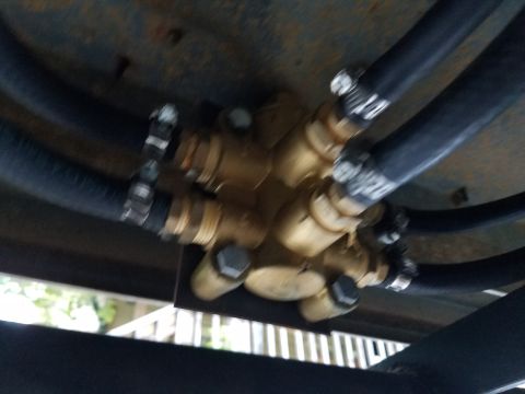1988 Ford Bronco - Close-up of a brass fuel selector valve with multiple hoses connected, likely part of a vehicle's fuel system.