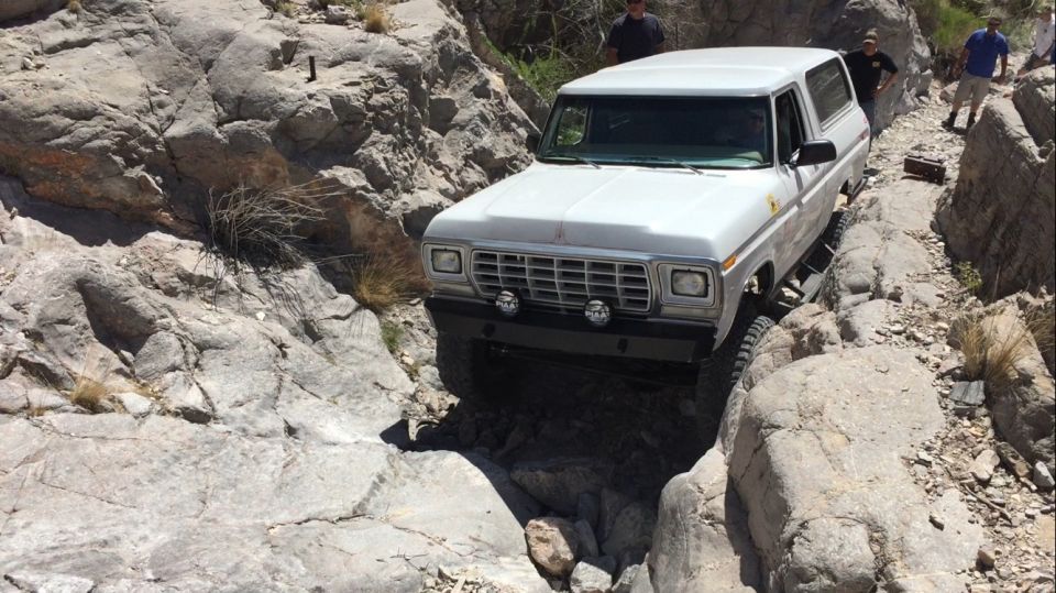 White SUV navigating a rocky canyon, front 3/4 view. Visible text: SUPERMOTORS