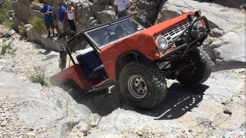 1979 Ford Bronco - 1979 Ford Bronco tackling a challenging off-road course with spectators observing.