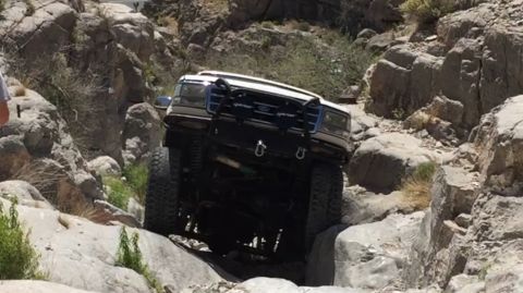 1979 Ford Bronco - White Ford F-Series truck is shown navigating a difficult rocky off-road trail.