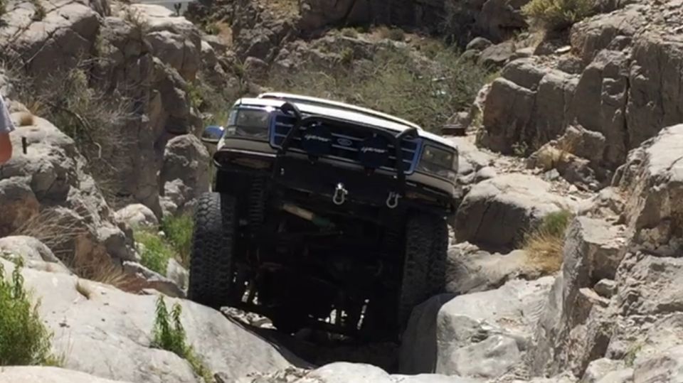 White Ford F-Series truck navigating a rocky off-road trail