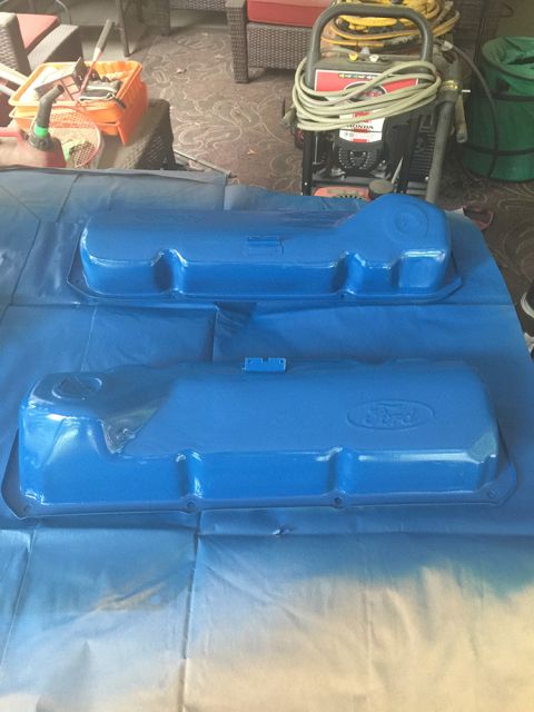 1978 Ford Bronco - Two blue Ford valve covers are shown on a blue tarp, with a pressure washer and painting supplies in the background.