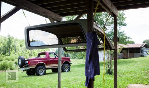 1995 Ford Bronco - A red Ford Bronco is parked outside with its top removed and suspended overhead.