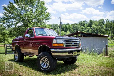 1995 Ford Bronco - This lifted 1995 Ford Bronco is parked in a rural setting with a shed in the background.