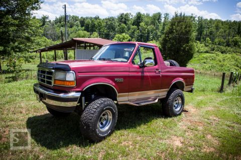 1995 Ford Bronco - This lifted Ford Bronco is shown in a rural setting with a wooded area and a rustic shed.
