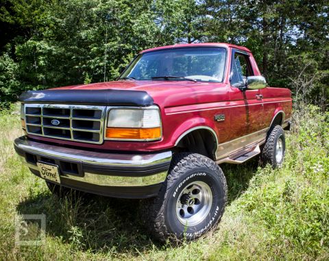 1995 Ford Bronco - A red 1995 Ford Bronco is shown from a three-quarter front angle, parked outdoors.