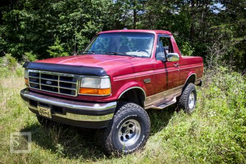 1995 Ford Bronco - Red 1995 Ford Bronco with aftermarket wheels and tires, parked outdoors.