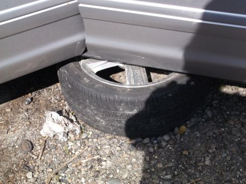 1999 Mercury Grand Marquis - A flat tire is visible beneath the side door of a gray vehicle.