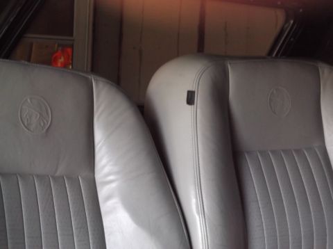 1999 Mercury Grand Marquis - The interior of a vehicle shows two front leather seats with embossed circular emblems.