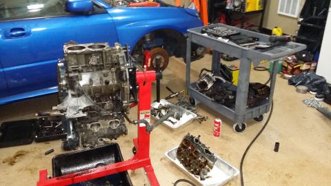 2007 Subaru Impreza - Engine block and parts laid out next to a blue Subaru, suggesting an engine build or repair.