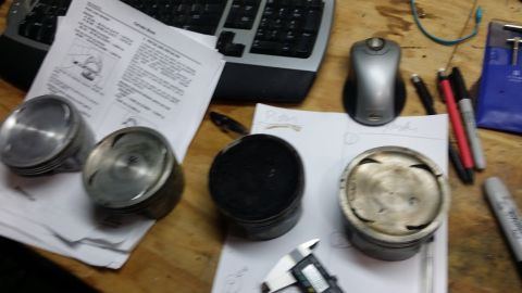 2007 Subaru Impreza - Engine pistons and technical diagrams are laid out on a workbench, suggesting a mechanical repair or build.