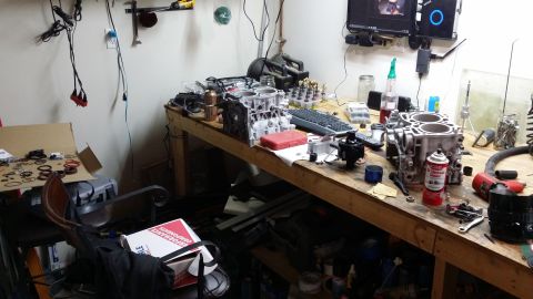 2007 Subaru Impreza - Various engine components and tools are laid out on a cluttered workbench, suggesting an ongoing repair or build.