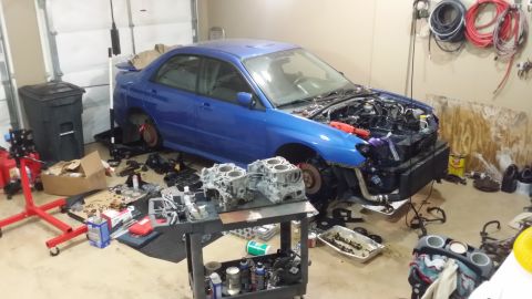 2007 Subaru Impreza - A blue Subaru Impreza is in a garage with its front end disassembled and engine parts laid out.