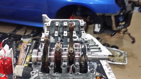 2007 Subaru Impreza - Disassembled engine block with crankshaft and connecting rods, with a blue vehicle in the background.