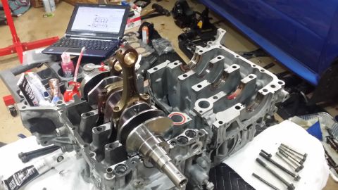 2007 Subaru Impreza - Engine block assembly with crankshaft and connecting rod, alongside a laptop displaying technical diagrams.