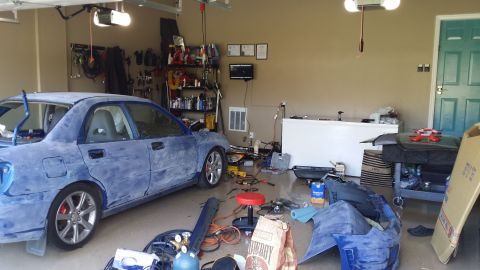 2007 Subaru Impreza - A blue Subaru Impreza is parked in a garage, surrounded by tools and car parts, with its hood open.