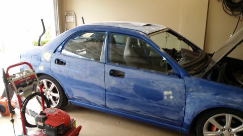 2007 Subaru Impreza - A blue sedan is shown in a garage with its hood open and primer patches on the body, indicating ongoing bodywork.