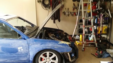 2007 Subaru Impreza - 2007 Subaru Impreza in garage with hood up, undergoing engine work and body repairs.