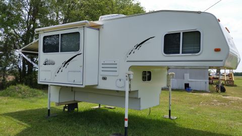1967 Ford Mustang - A white truck camper with a slide-out section and an awning is parked on a grassy area.