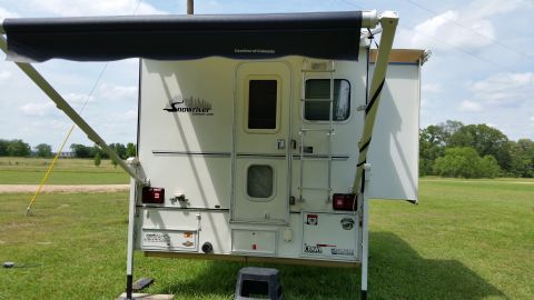 1967 Ford Mustang - This Snowriver truck camper is set up in a field with its awning extended.