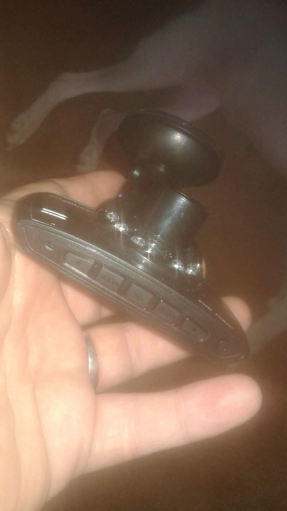Hand holding a black dash cam with suction cup mount
