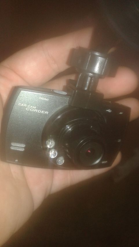 1996 Ford Bronco - A hand holds a black car dash camcorder, showing its lens and text labels.