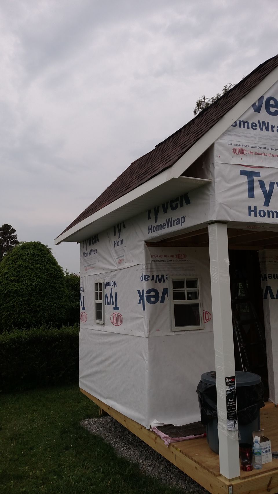 house exterior covered in Tyvek wrap, with a roof and two windows visible