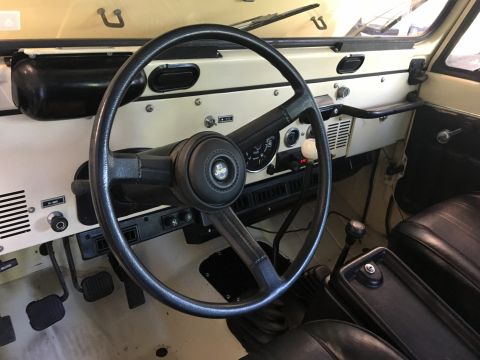 1986 Jeep Wagoneer - The interior of a Jeep shows a cream dashboard and black steering wheel, with a watermark at the bottom right.