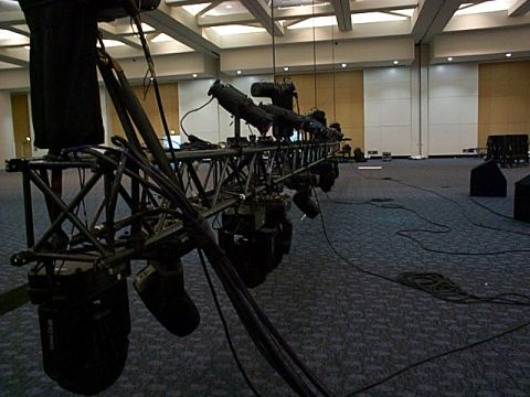1994 Ford Bronco - A complex stage lighting truss system is set up in a large convention hall, with cables running across the carpeted floor.