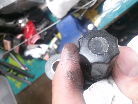 1996 Ford Bronco - Close-up of a hand holding a black knob with a silver center, with tape nearby.