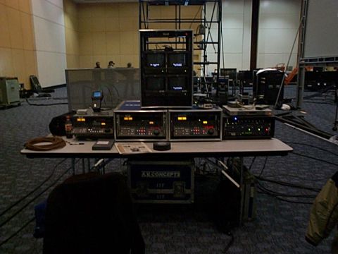 1994 Ford Bronco - A collection of audio-visual equipment, including monitors and mixers, is set up on a table in a large room.