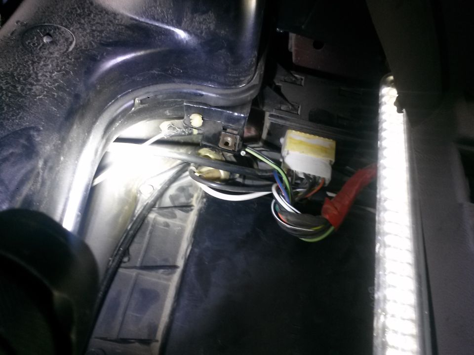 Wiring harness with yellow-taped connector and red boot, viewed from inside vehicle